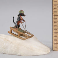 Sculpture miniature antique autrichienne en bronze représentant un teckel faisant du traîneau dans la neige.