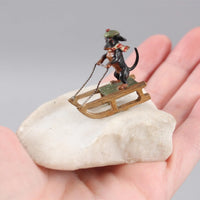 Sculpture miniature antique autrichienne en bronze représentant un teckel faisant du traîneau dans la neige.