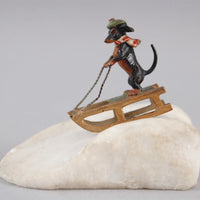 Sculpture miniature antique autrichienne en bronze représentant un teckel faisant du traîneau dans la neige.